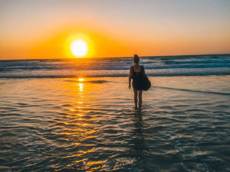 solo female traveller on beach during sunset
