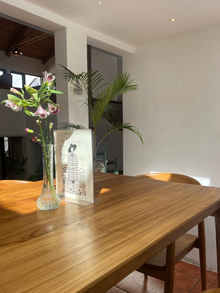 photo of table with small flower vase and cafe sign with white crisp walls in background