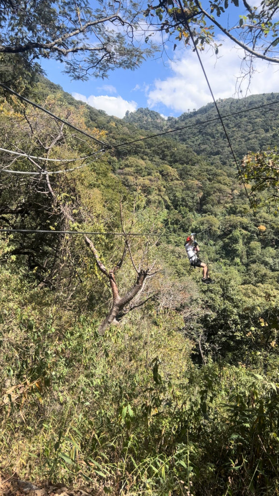 photo showing josh come down the treetop zip-lines surrounded by the atitlan nature reserve forest