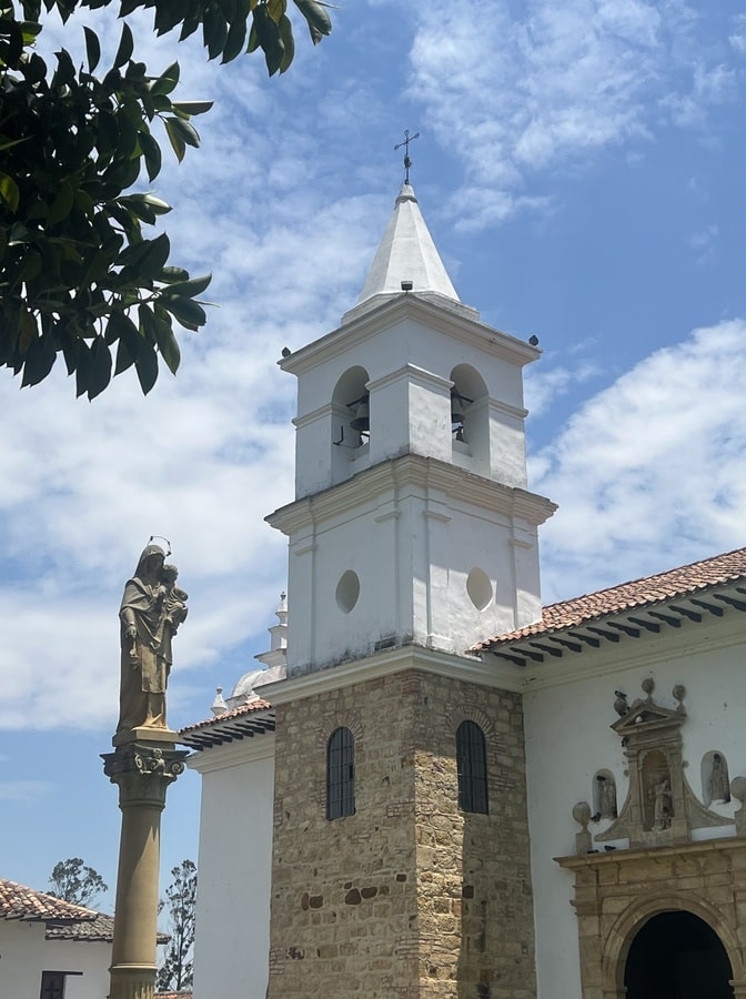 photo of church tower and a statue in villa de leyva