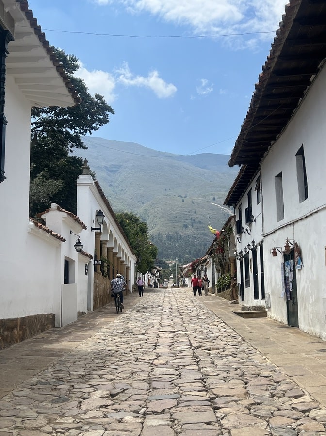 photo of a cobbled street in villa de leyva with white painted buildings on both sides