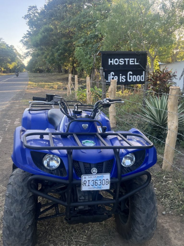 photo showing hostel life is good sign with a blue ATV in the foreground