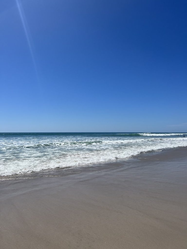 photo of blue sky and the waves crashing on the sand at playa santa teresa, costa rica