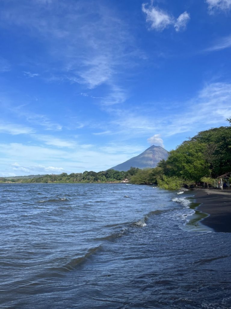 photo of the ocean on ometepe island with trees and a distant view of Volcano Concepcion
