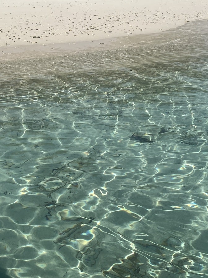 photo of the crystal clear blue tinted water meeting white soft sand