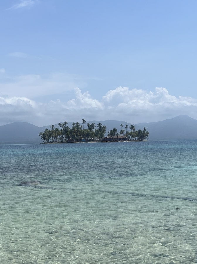 photo of the ocean with a circular shaped island surrounded by trees