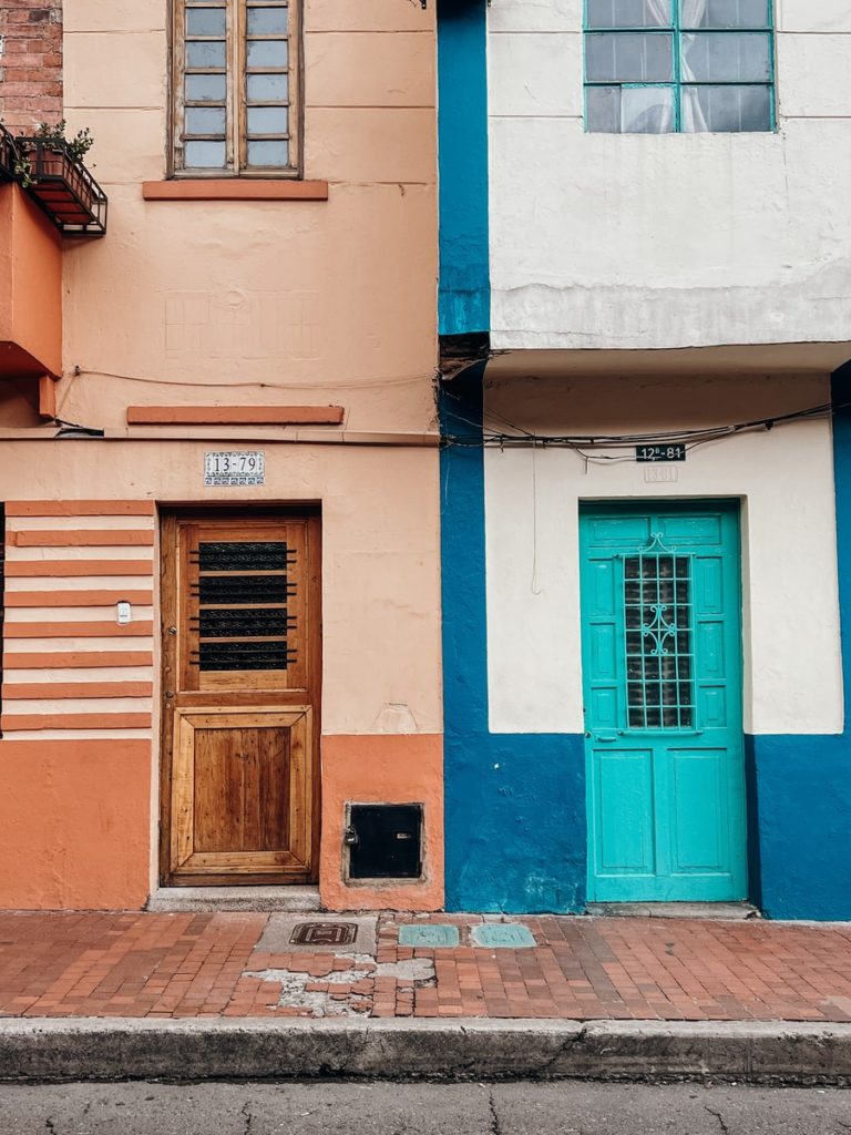 photo of two colourful buildings in la candelaria bogota, one blue one terracotta
