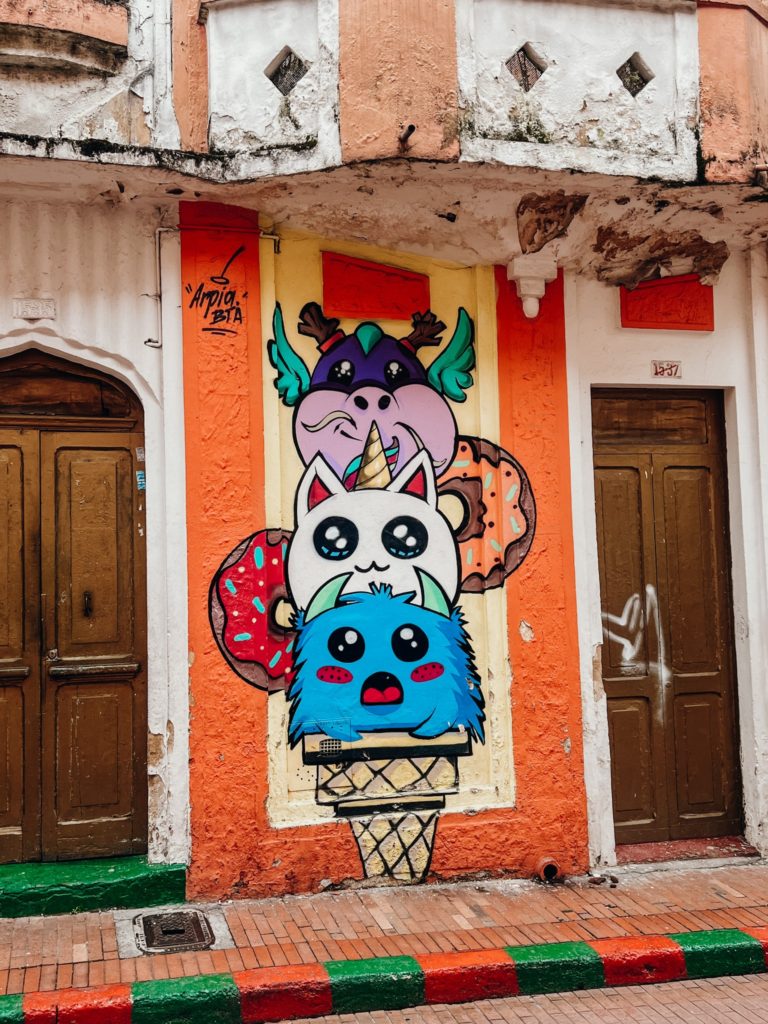 photo of street art in la candelaria, with 3 cartoon style characters on a orange building
