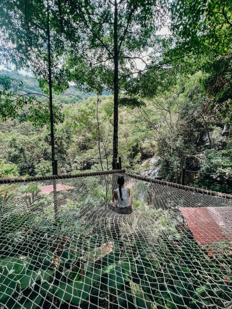 photo of a woman sitting on a net overlooking nature of minca