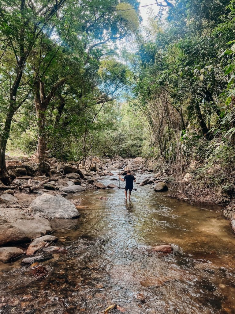 photo of a man sitting on a swim in the middle of a river in minca