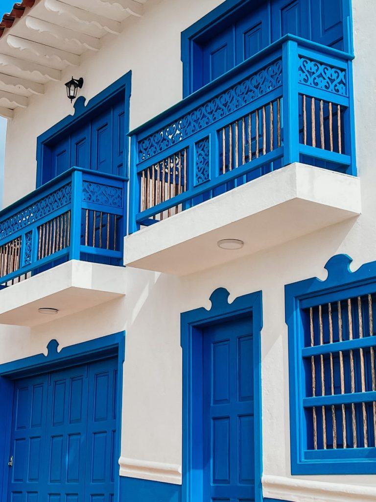photo of white building with blue doors, windows and balcony's in jerico, colombia