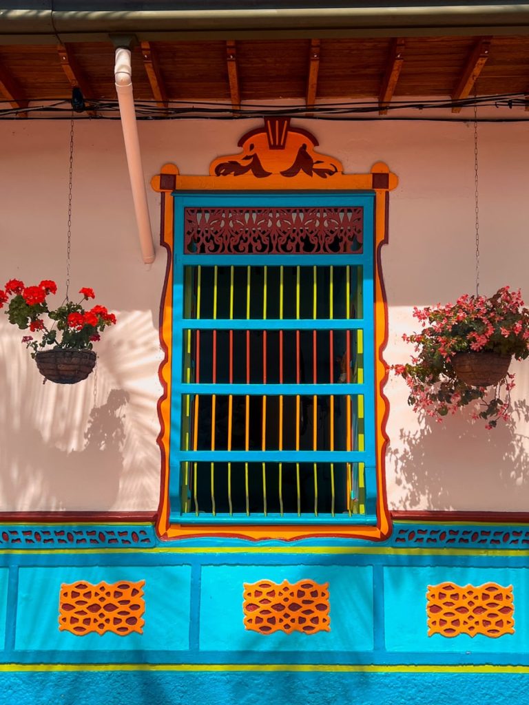 photo of colourful blue window in guatape with hanging plants either side and detailing