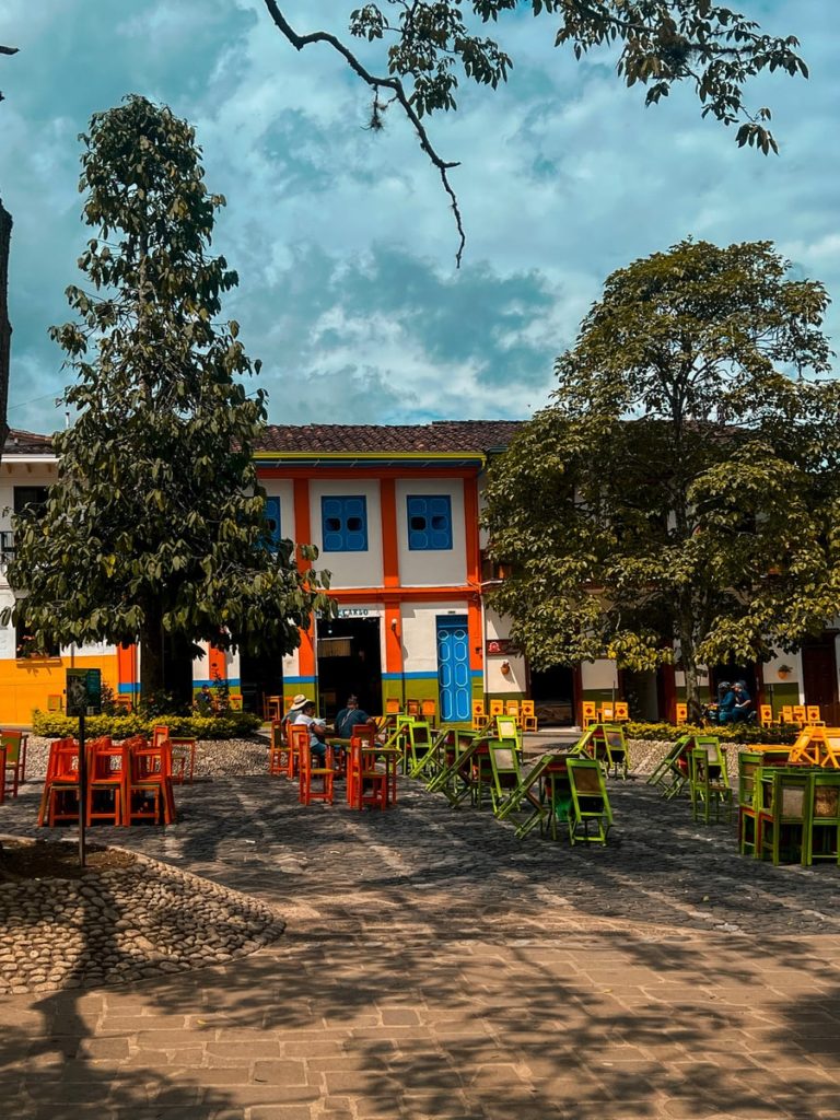 photo showing colourful seats, tables and buildings in the main square of jardin colombia.