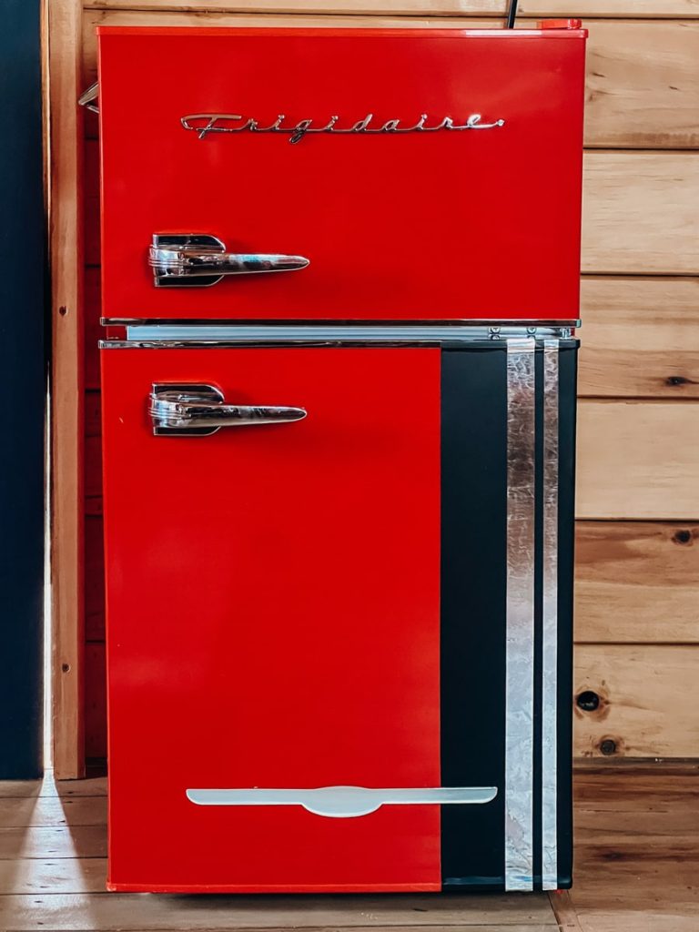 photo of a super vibrant red fridge with wood wall in the background