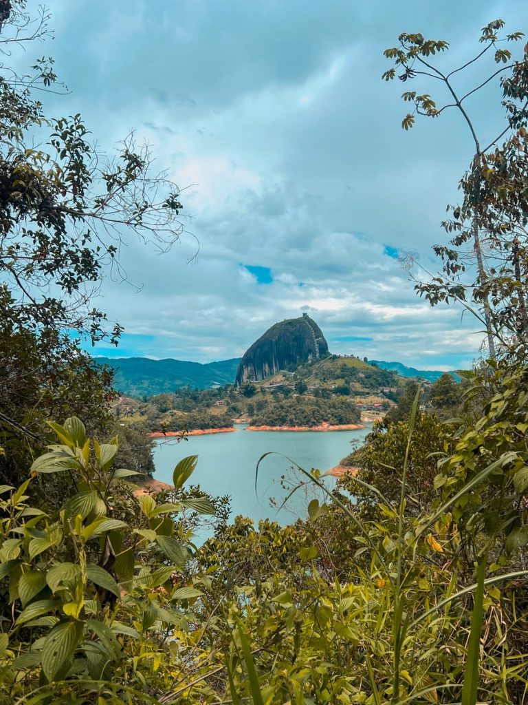 photo of piedra del peñol between greenery and the reservoir