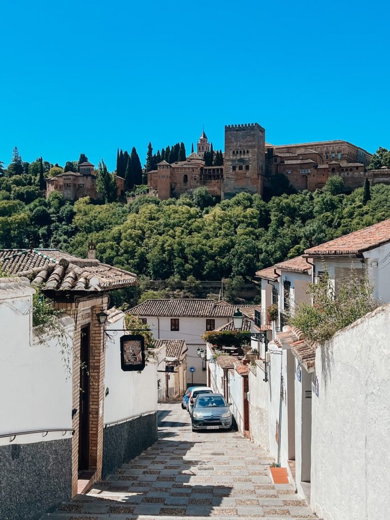 streets of granada with alhambra towering in the background