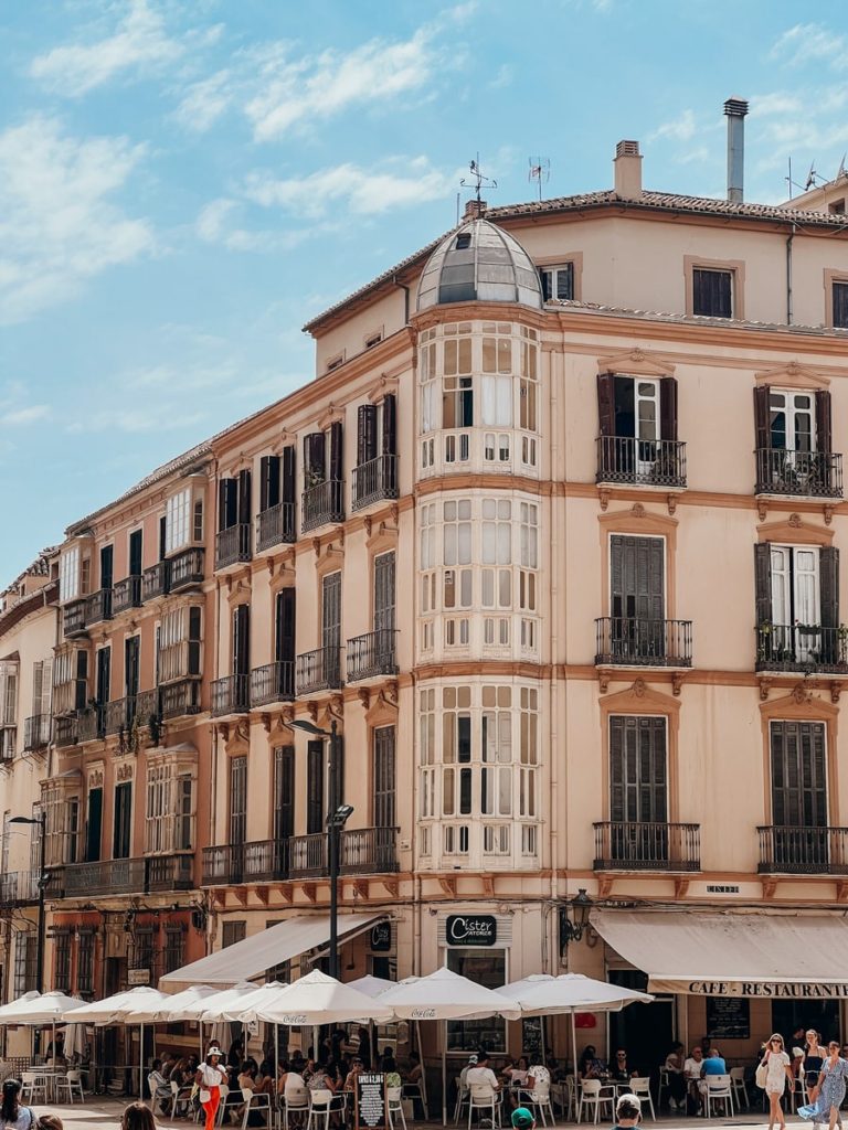 photo of a building in malaga with outside cafe seating in the bottom of the photo