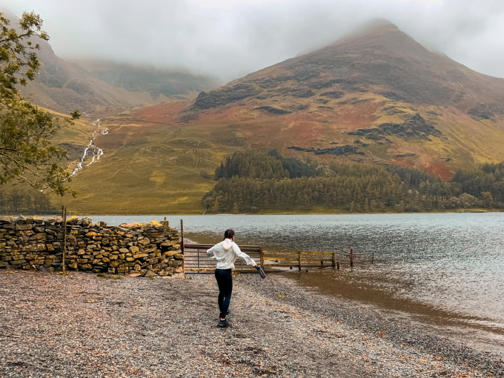Girl infront of Buttermere lake on a cloudy day with mountain peaks in the background