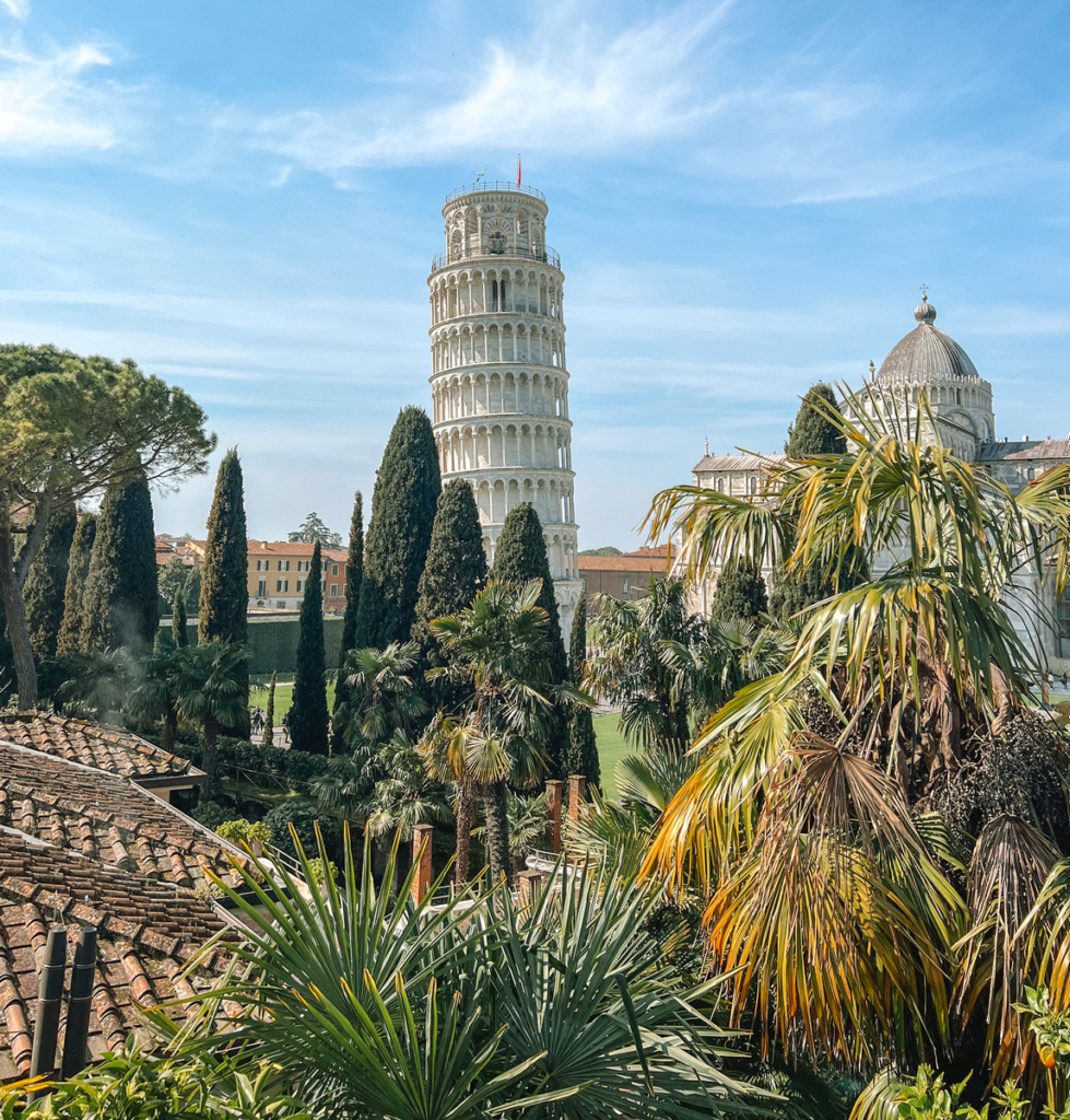 photo of leaning tower of pisa with a lot of shrubbery and trees in front